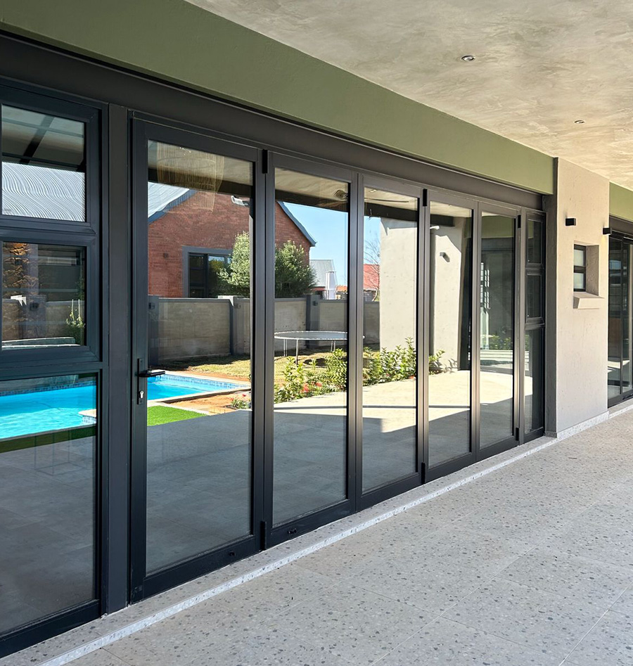 Folding-stacking aluminium doors opened onto a pool and garden at a Gauteng home