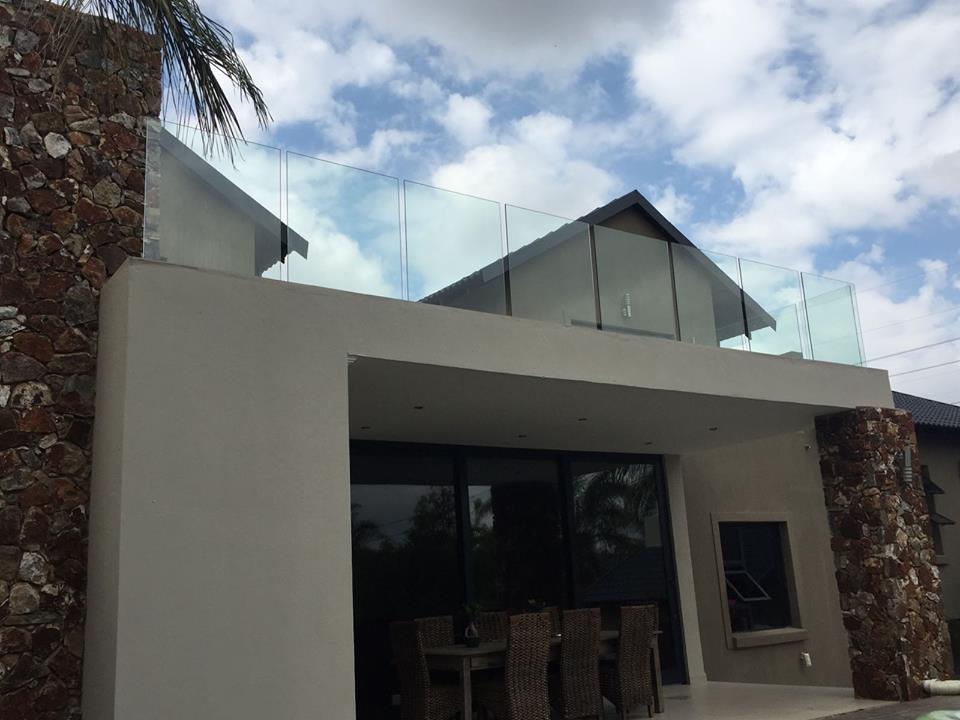 Frameless glass balustrade on a home exterior with stone cladding