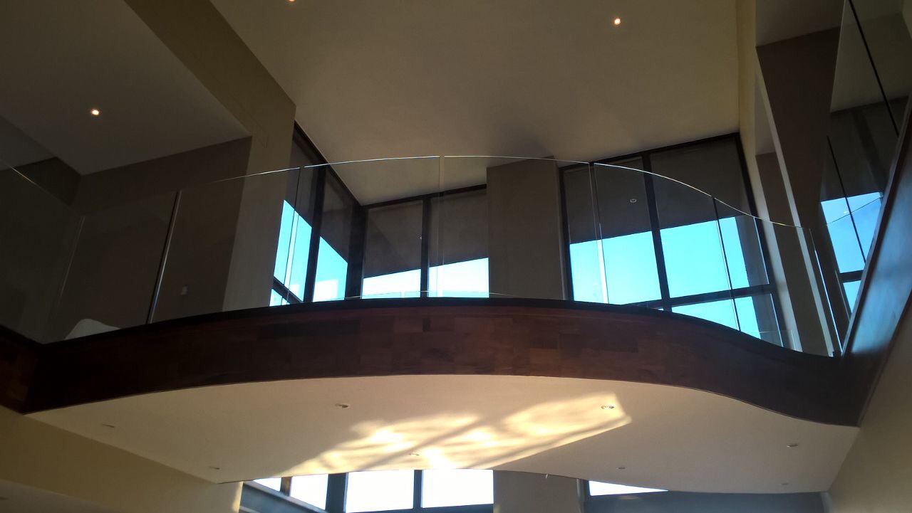 Curved frameless glass balustrade installed inside a modern home