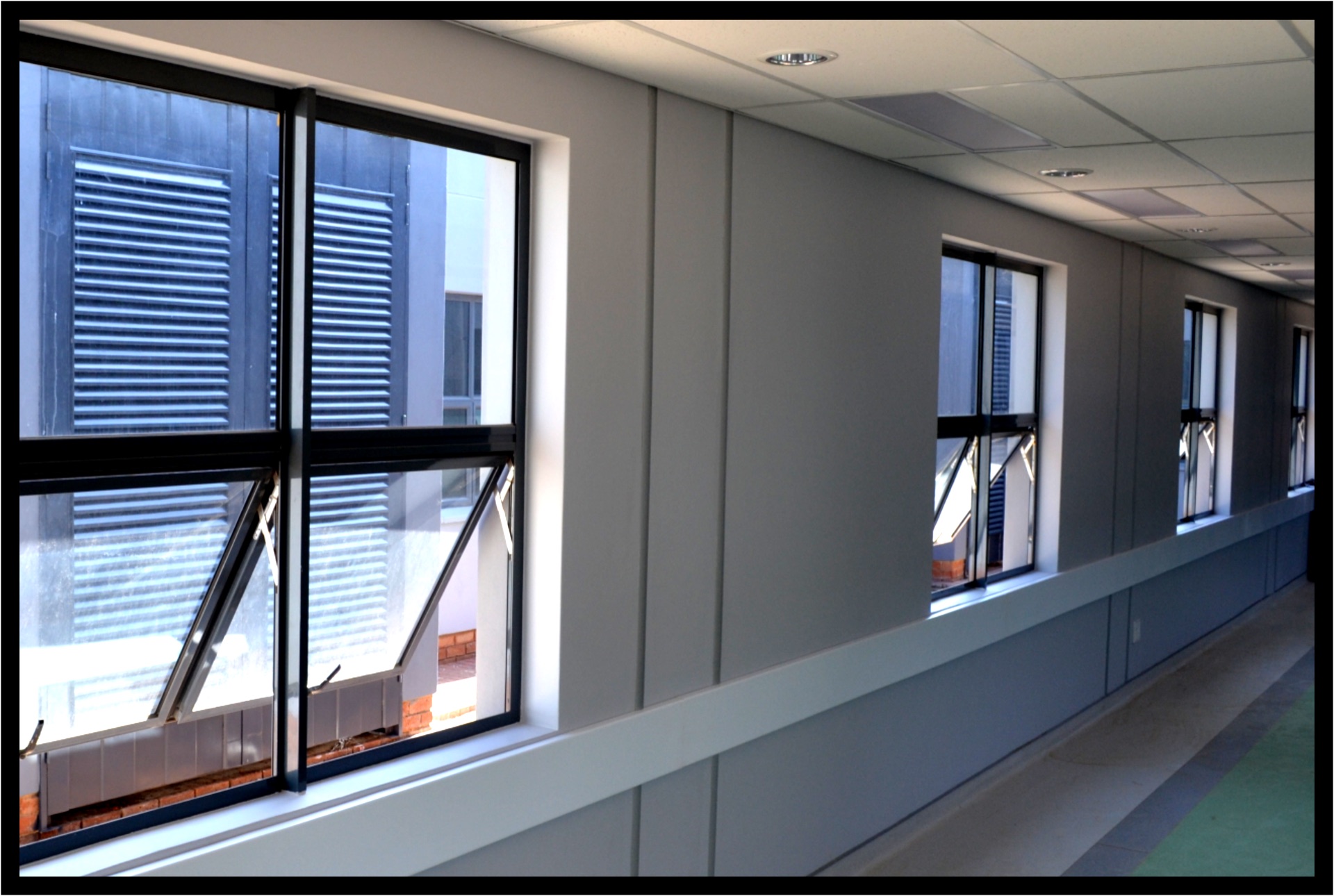 Row of aluminium-framed windows installed along a commercial corridor
